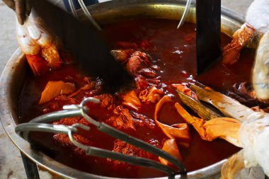 Batik ikat 'te çalışan Taylandlı zanaatkar, Tayland' ın Uthai Thani kentindeki Ban Rai şehrinde Baan Phu Chuang 'da el işi atölyesinde kaynatılmış Bixa orellana fıstığının doğal turuncu rengini boyuyor.