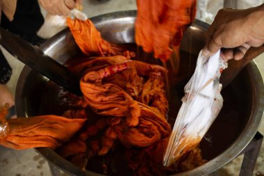 Taylandlılar Batik ikat öğrenmeyi öğreniyor ve Tayland 'ın Uthai Thani kentindeki Ban Rai' de Baan Phu Chuang atölyesinde el yapımı el sanatları atölyesinde Bixa orellana fıstığından doğal turuncu boya yapıyorlar.