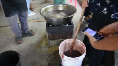 Batik ikat 'te çalışan Taylandlı bir zanaatkar, Tayland' ın Uthai Thani kentindeki Ban Rai 'de Baan Phu Chuang atölyesinde el yapımı el sanatları atölyesinde kaynamış plastikten yapılan doğal pembe boyayı boyuyor.