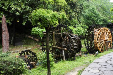 Ancient building wooden turbine baler or antique architecture wood water wheels chinese style in canal for treatment water on pool pond in Huanglong Dong Scenic Area at Zhangjiajie city in Hunan China clipart