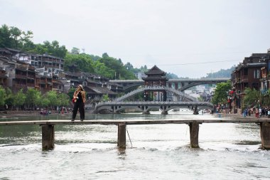 Taylandlı kadın gezginler seyahat ederken fotoğraf çektirip tuojiang nehrini ve tarihi binaları ziyaret ederler. Xiangxi Phoenix antik şehir Fenghuang 'ın Çin' in Hunan kentindeki tarihi yapısını ziyaret ederler.