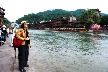 Taylandlı kadın gezginler seyahat ediyor. Fotoğraf makinesi kullanıyorlar. Xiangxi Phoenix Antik Şehir Fenghuang 'ın tarihi mimarisini 9 Mayıs 2024' te Hunan, Çin 'de çekiyorlar.