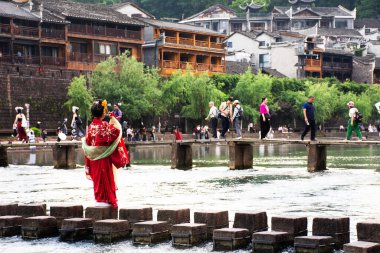 Çinli gezginler tuojiang nehri ve tarihi Xiangxi Antik Kenti veya Antik Fenghuang Eski Kasabası 'nda 9 Mayıs 2024 tarihinde Çin' in Hunan kentinde fotoğraf çektirmek için geleneksel kabile kıyafetleri kiralarlar.