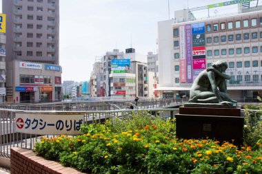 7 Temmuz 2024 'te Kanagawa Kanto, Japonya' da Fujisawa istasyonundaki modern binaları, bronz heykel ve yaşam tarzı Japon yerlileri ile birlikte, Kanagawa 'daki Kamakura Enoshima kentinin manzarasına bakın.