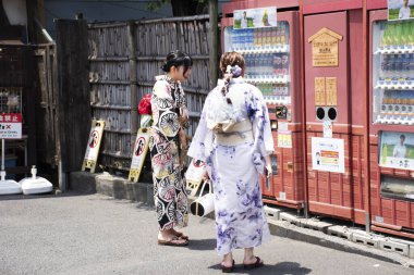 Gezgin Japon kadın geleneksel kimono giysisi giyer. 4 Temmuz 2024 'te Tokyo, Japonya' da, Asakusa 'da Shin Nakamise dori alışveriş caddesi pazarında otomatik içecek otomatı satın alır.