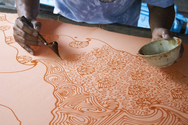 Craftsmanship of thai professional artist working use Tjanting tool or canting equipment and beeswax drawing batik ikat in handmade studio handicrafts workshop at Pak Bara of La ngu in Satun, Thailand