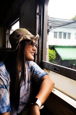 Travelers thai women people sitting on railway for journey explorer and portrait posing for take photo at window train travel visit from Wongwian Yai to Maha Chai at Thonburi city in Bangkok, Thailand clipart