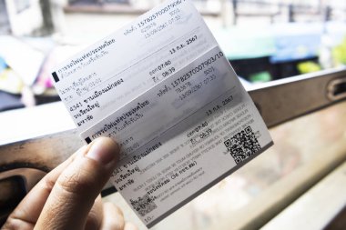 Taylandlı gezginler, 13 Eylül 2024 tarihinde Tayland 'ın Bangkok şehrinde Wongwian Yai tren istasyonundan Thonburi şehrindeki Maha Chai duraklarına seyahat için kağıt bilet göstermektedir.