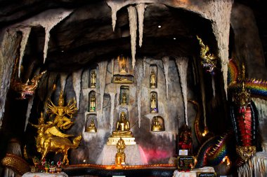 Ancient variety buddha and naga guardian holy deity angel in antique tunnel cave worship for thai people travel visit respect praying blessing at Wat Bua Khwan on July 29, 2024 in Nonthaburi, Thailand clipart