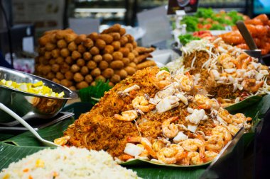 Geleneksel yerel sokak yemekleri Tayland 'ın Bangkok şehrinde ICONSIAM' da yabancı gezginler tarafından seçilen Sook Siyam pazarından içki satın alınarak birçok çeşit kızarmış erişte ve kızarmış pirinç pişiriliyor.