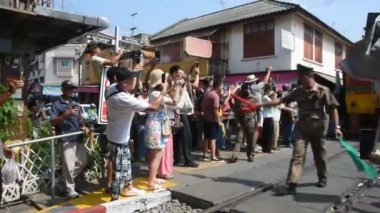 Taylandlılar için Maeklong Demiryolu Seyahat Treni Talad Rom Hub 'da ya da şemsiye pazarında koşan yabancı gezginler için. 17 Kasım 2024' te Samut Songkhram, Tayland 'da hediye ürünleri satın alıyorlar.