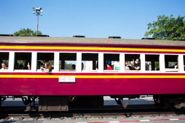 Taylandlı ve yabancı yolcu yolcuları klasik Bogie Lokomotif treniyle Kwai Nehri üzerindeki çelik tren köprüsünde 26 Aralık 2024 'te Kanchanaburi, Tayland' daki Tham krasae mağarasına gidiyorlar.