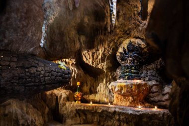 Buddha meditation protect cover head by mythical serpent or Naka Prok Buddha Sheltered in Naga Cave Tham Nakee for thai people travel visit respect praying at Wat Khae Temple in Suphan Buri, Thailand clipart