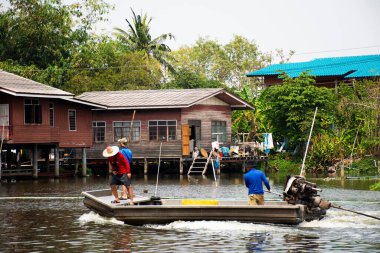 Taylandlı işçiler ve dümenci uzun kuyruk teknesi Khlong Bangkok Noi Kanalı 'nda yelken açıyor. 23 Şubat 2025' te Tayland, Nonthaburi 'de Bang Kruai tapınağındaki Wat Utthayan tapınağındaki atık nehrini temizliyorlar.