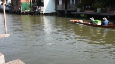 Tayland dümencisi Khlong Bang Luang 'da uzun bir tekne turuyla gezginler için seyahat ediyor. 2 Mart 2025' te Bangkok, Tayland 'da antika retro eviyle yüzen pazar ve sanatçı evi Bangkok' u ziyaret ediyorlar.