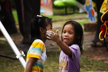 Yerel çocuklar yanak yanaklarına beyaz kil doldurucu tozu sürerler. Songkran Festivali 'ne katılan kız çocukları ya da 13 Nisan 2025' te Ayutthaya, Tayland 'da düzenlenen Tayland Yeni Yılı kutlamalarına katılır.