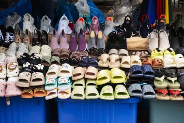 Tayland 'da 14 Nisan 2025' te Talad Nam Taling Chan yüzer pazarındaki yerel mağazadaki erkekler için ayakkabı, spor ayakkabısı, plastik terlik ve deri ayakkabılar satan Taylandlı kadınlar.