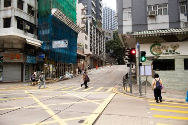 26 Nisan 2025 'te Hong Kong, Çin' de trafik ışıklarıyla caddede yürüyen Hong Kong şehrinin gökdelen manzaralı şehir manzaralı evini ve yaşam tarzını izleyin.