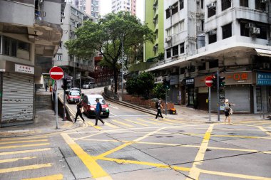 26 Nisan 2025 'te Hong Kong, Çin' de trafik ışıklarıyla caddede yürüyen Hong Kong şehrinin gökdelen manzaralı şehir manzaralı evini ve yaşam tarzını izleyin.