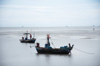 Manzara deniz manzarası ve bulutlar deniz okyanusunda dalgalanır ve Tayland balıkçıları ahşap balıkçı teknesi veya balıkçı teknesi durur Phetchaburi, Tayland 'daki Phetburi sahillerinde balık ve deniz yaşamı yakalarlar.