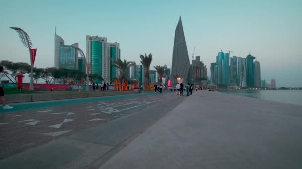 ドーハ カタールのドーハ コーニッチが日没のショットでズームし 地元の人々や訪問者とFifaワールドカップカタール2022のためのカタールの準備を示します — ストック動画