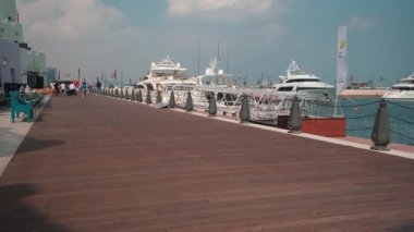 Katar 'ın Doha kentindeki eski Doha limanı (Mina Bölgesi) öğleden sonra, yerel halk ve ziyaretçilerin yürüdüğü kafe, restoran ve yolcu gemilerini gösteren bir fotoğraf.