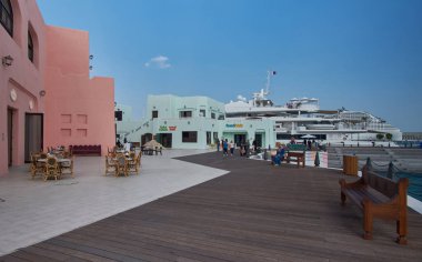 Old Doha port (Mina District) in Doha, Qatar afternoon shot showing cafe, restaurants and cruise ships with locals and visitors walking