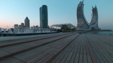 Lusail Corniche at the marina in Lusail city, Qatar sunset shot showing fountain, people walking on the promenade with skyline in background