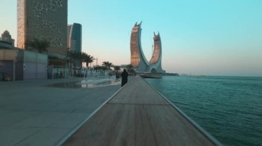 Lusail Corniche at the marina in Lusail city, Qatar sunset shot showing fountain, people walking on the promenade with skyline in background