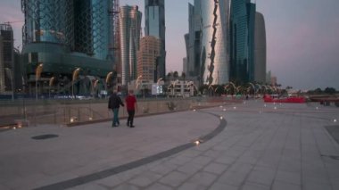 Doha corniche, Doha, Katar gün batımında yakınlaşıyorlar. Batı körfezindeki gezinti alanını yerli halk ve ziyaretçilerle birlikte gösteriyorlar. 