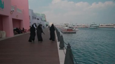 Old Doha port (Mina District) in Doha, Qatar afternoon shot showing cafe, restaurants and cruise ships with locals and visitors walking