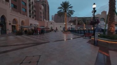 Porto Arabistan İnci Doha 'da, Katar' ın günbatımında kış çekimleri gezinti güvertesinde yürüyen insanları gösteriyor. 