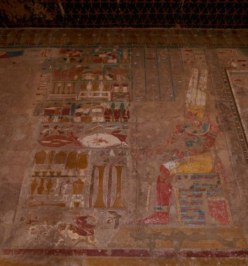Temple of Hatshepsut, Luxor Egypt showing colorful scene representing the god Ra seated on his throne having a large table of offerings offered to him from the queen erased as usual by Thutmose III
