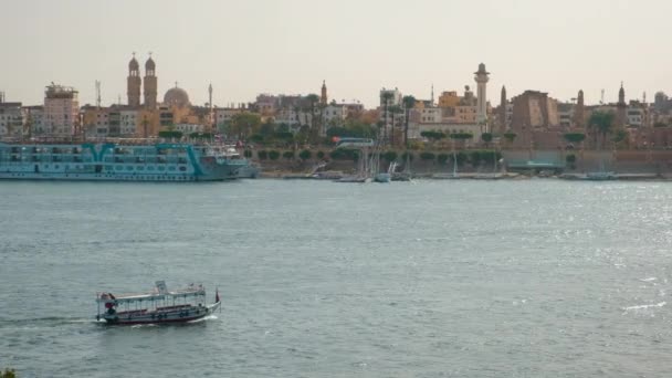 エジプトのルクソール東岸のクルーズ船 フェルーカスとルクソール神殿でナイル川を示す西岸から撮影された昼光ズーム — ストック動画