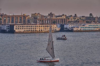 Luxor, Mısır 'ın batı yakasından çekilen gün batımı Feluccas, yolcu gemileri ve Doğu yakasındaki Luxor Tapınağı ile Nil Nehri' ni gösteriyor.