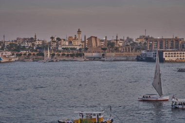 Luxor, Mısır 'ın batı yakasından çekilen gün batımı Feluccas, yolcu gemileri ve Doğu yakasındaki Luxor Tapınağı ile Nil Nehri' ni gösteriyor.