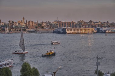 Luxor, Mısır 'ın batı yakasından çekilen gün batımı Feluccas, yolcu gemileri ve Doğu yakasındaki Luxor Tapınağı ile Nil Nehri' ni gösteriyor.