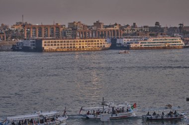 Luxor, Mısır 'ın batı yakasından çekilen gün batımı Feluccas, yolcu gemileri ve Doğu yakasındaki Luxor Tapınağı ile Nil Nehri' ni gösteriyor.