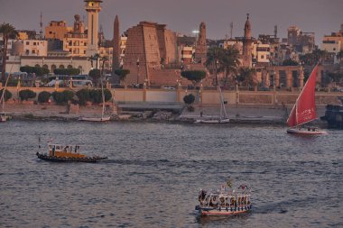 Luxor ,Egypt sunset shot from west bank showing Nile river with  Feluccas, cruise ships  and Luxor Temple in East bank