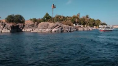 Nile river in Aswan, Egypt afternoon shot showing feluccas and boats in the river in front of entrance to  Aswan Botanical Garden