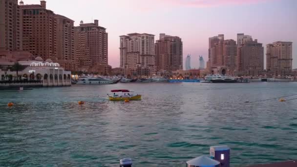 ポルト アラビア マリーナ パール ドーハ カタールの夕日が背景に住宅建築物とマリーナにドッキング豪華なヨットやボートを示すショット — ストック動画