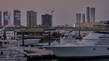 Lusail marina in Lusail city, Qatar sunset view with Yachts and boats with Qatar flag ,Lusail skyline and clouds in the sky in  in background