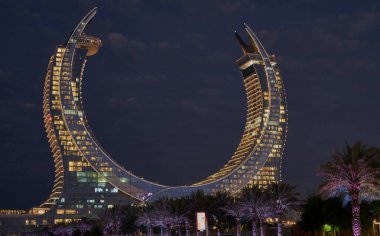 Katara Hospitality Tower, or Lusail Katara Hotel North Tower in Lusail, Qatar at dusk showing the unique architecture of the illuminated tower