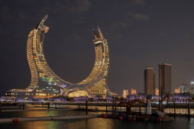 Katara Hospitality Tower, or Lusail Katara Hotel North Tower in Lusail, Qatar at dusk showing the unique architecture of the illuminated tower