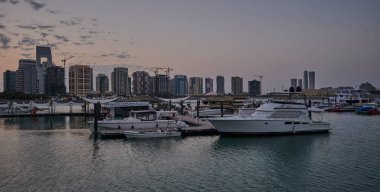 Lusail marina in Lusail city, Qatar sunset view with Yachts and boats with Qatar flag ,Lusail skyline and clouds in the sky in  in background