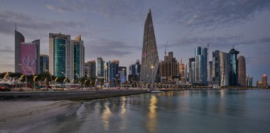 Gün batımında Corniche gezinti alanından Doha Katar gökdelenlerinin Arap körfezine yansıdığını gösteren gökdelenler.