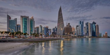 Gün batımında Corniche gezinti alanından Doha Katar gökdelenlerinin Arap körfezine yansıdığını gösteren gökdelenler.