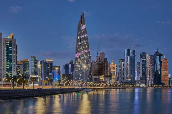 Stock image Doha Qatar skyline from corniche promenade at dusk showing West Bay skyscrapers lights reflected in the Arabic gulf