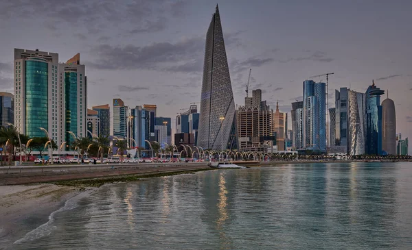 stock image Doha Qatar skyline from corniche promenade at sunset showing West Bay skyscrapers lights reflected in the Arabic gulf