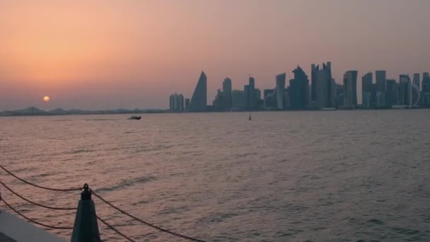 ドーハのミナ地区 旧ドーハ港 からのドーハのスカイライン カタールの日没は西湾の高層ビルと空の雲が背景に太陽を示しています — ストック動画